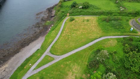 small park with pathways and vibrant green grass by the shore of valentia river