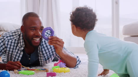 young black father lying on floor playing with his young son