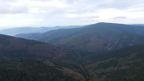 Aerial-view-of-the-top-of-the-hills-with-the-forest-lying-below-and-lots-of-smaller-peaks-and-nature