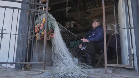 elderly man talking about his art of mending fishing nets. static