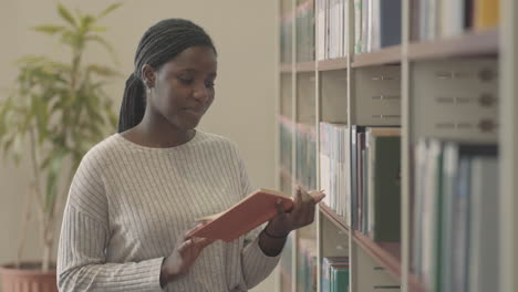 pretty black woman reading a book in the library