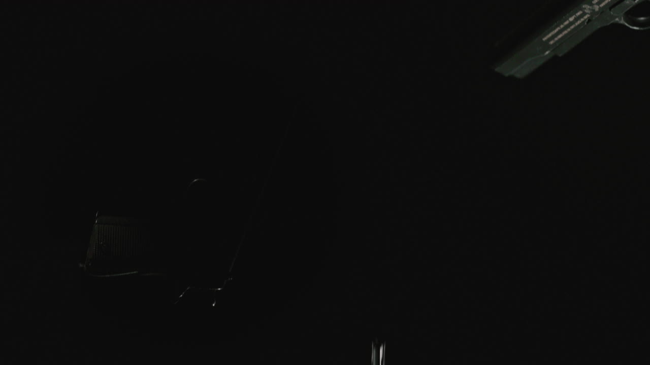 Pistols on the dark background and in blinking lights are falling in slowmotion