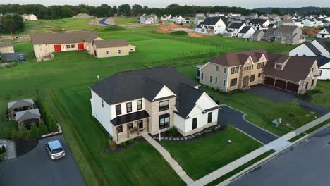 modern suburban housing development in america. new single-family homes,wide streets, green lawns and early morning light in peaceful neighborhood.aerial approaching shot. quiet suburb district in usa