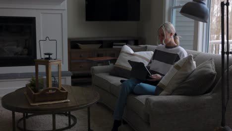 woman-walking-to-the-couch-to-lay-down-and-scroll-through-tablet-while-drinking-coffee-in-a-nice-house