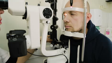 Man taking eye test examination. Ophthalmologist doing eye test on man patient in clinic