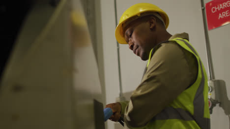 african american male worker wearing safety suit with helmet in warehouse