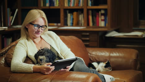 a woman reads a book in a tablet sits in the luxurious back of the library