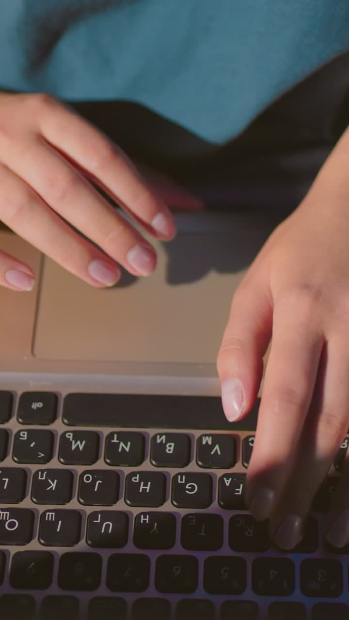 primer plano de una mecanógrafa escribiendo en una computadora portátil al aire libre por la noche con las manos iluminadas por el brillo de la pantalla, los vaqueros de denim se reflejan sutilmente en la superficie de la computadora portatil, con una bolsa roja al lado