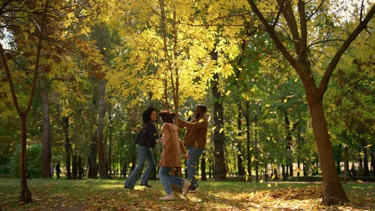 parco giochi per famiglie felici, corsa sotto le foglie dorate che cadono, tempo libero in giardino.