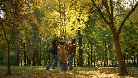 happy family play park run under falling golden leaves. leisure time in garden.