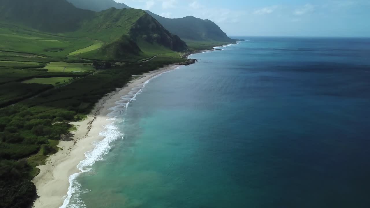 Tomada aérea com tilt up revelando a Praia de Makua no Havaí com o vale no horizonte
