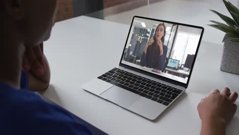 Mid-section-of-african-american-woman-having-a-video-call-on-laptop-with-female-colleague-at-office