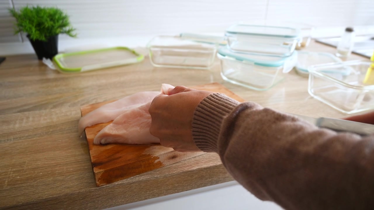 Primo piano di una donna che affetta pollo crudo