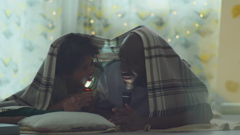 dad and little son playing with flashlights in bedroom
