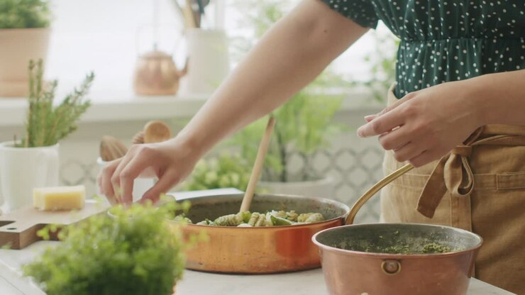 mujer de la cosecha añadiendo bolas de mozzarella a la pasta