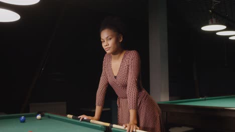 woman playing pool in a dark billiards hall