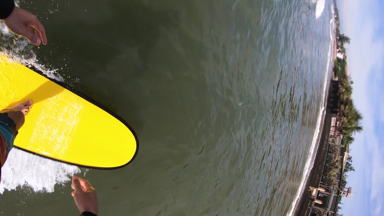 video vertical, pov gopro de una persona surfeando en una ola en una tabla de espuma y luego cayendo
