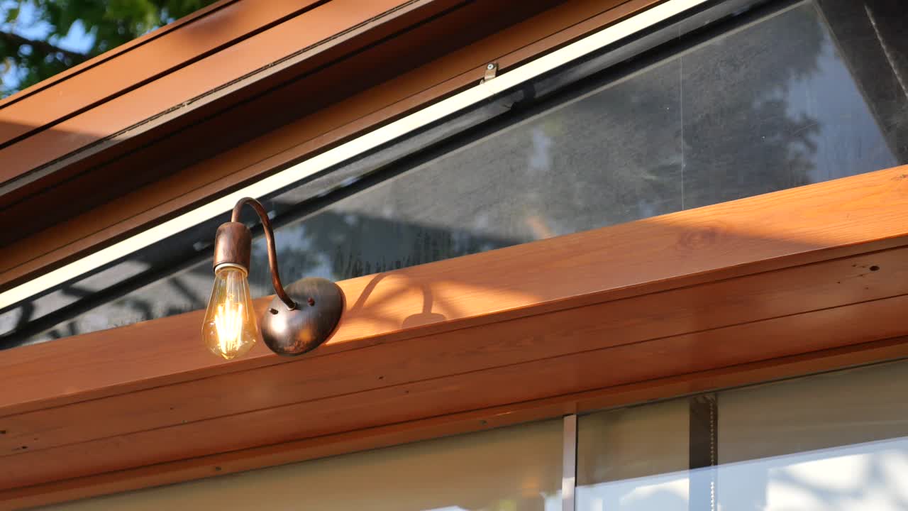 exterior de edificio de madera marrón con lámpara de pared de bronce