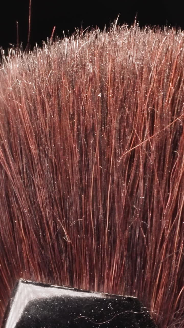 Professional cosmetic brush with long bristles for facial makeup on black background. Detailed product for applying blush at bright light macro