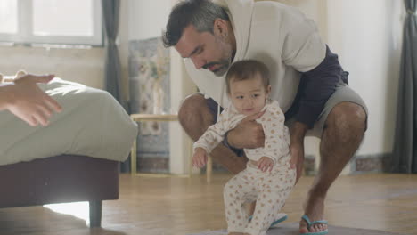 padres jóvenes felices enseñando a su linda niña dando sus primeros pasos en casa