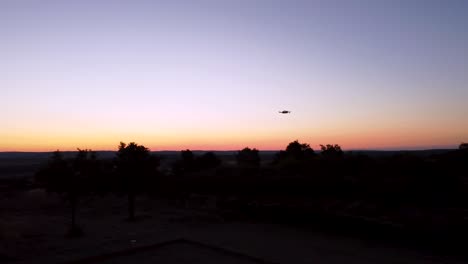 A small drone takes flight over fields in the early hours of the morning as the sun begins to rise