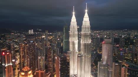 aerial view of iconic towers glowing in night lights, framed by the bustling city and illuminated skyline