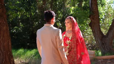 indian hindu groom walks towards his bride outdoor and kiss her on the cheek