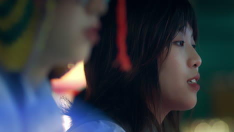 closeup of two asian girls focusing playing carnival game at night