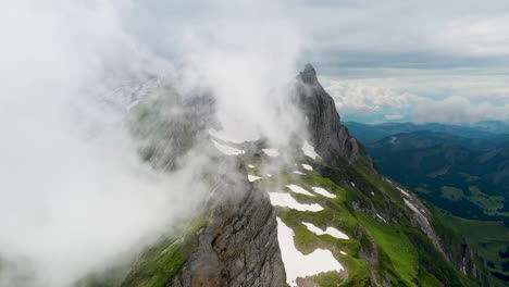 Cinematic-drone-shot-of-Altenalp-Turm,-with-clouds-covering-the-mountain
