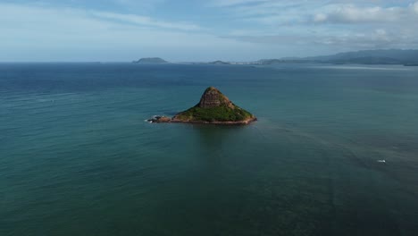 4K-cinematic-drone-shot-of-Chinaman's-Hat-in-Oahu-surrounded-by-calm-blue-water