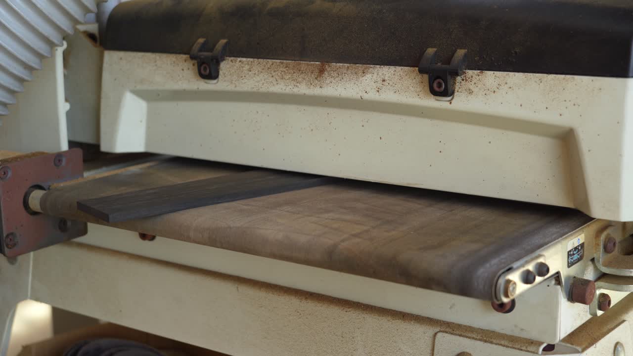 alimentación del diapasón de ébano a través de una lijadora de tambor