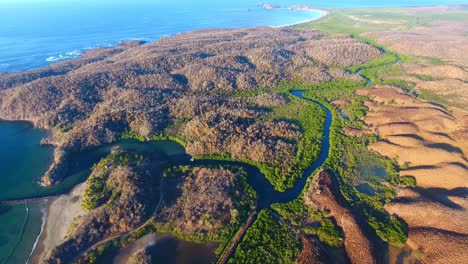 Vista-De-ángulo-Alto-Del-Estuario-Del-Río-Manglar-Cerca-Del-Borde-De-Los-Océanos-Con-Colinas-Desérticas-Marrones