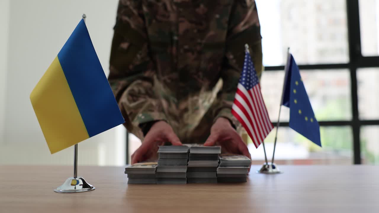 Military personnel with stacks of US dollar bills, flanked by Ukrainian, American, and European Union flags, symbolizing international financial support for Ukraine