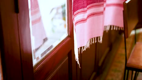 pink curtain gently swaying near wooden door in bangkok, thailand