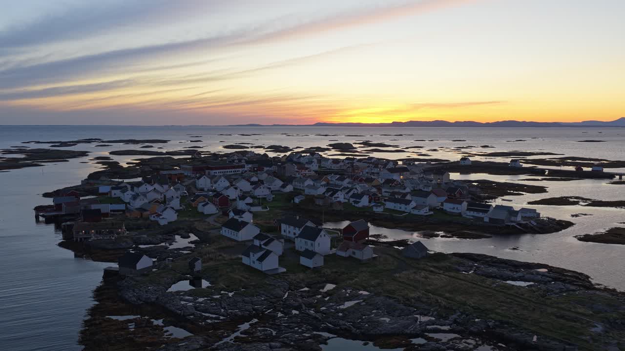 Ein Sonnenaufgang beleuchtet ein klassisches norwegisches Dorf mit Holzhäusern, aus der Luft.