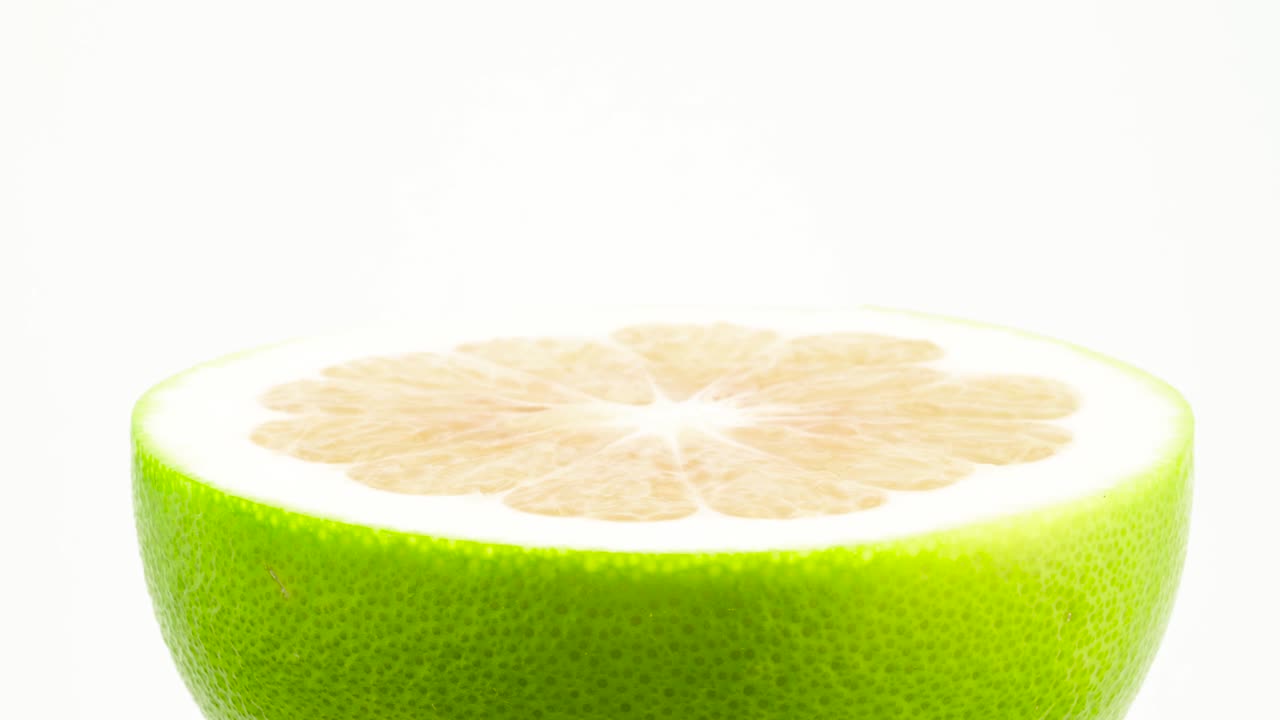una mitad de fruta verde dulce. girando en la mesa giratoria. aislado en el fondo blanco. primer plano. macro.