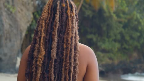 Natural-hair-girl-walks-along-the-shoreline-with-waves-crashing-in-the-distance