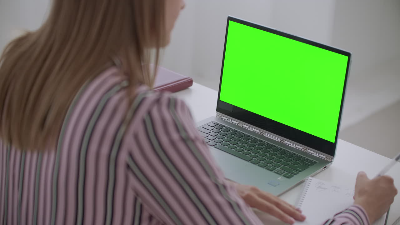 mujer está viendo un seminario web en una computadora portátil con pantalla verde para tecnología chroma key e-learning y trabajo remoto