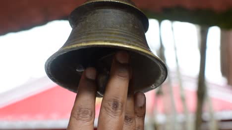 Visitor-ringing-bell-hanging-at-temple-ceiling