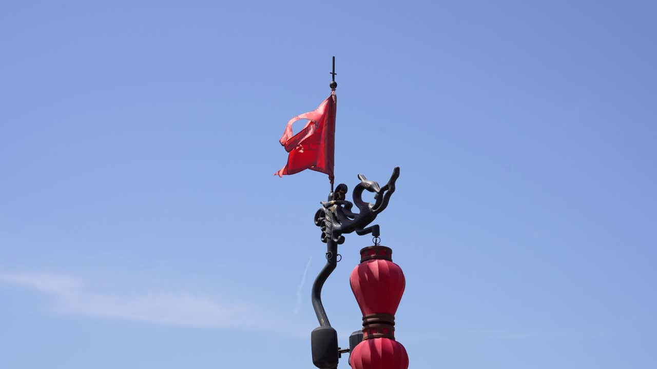 Red Flag and lanterns wave in wind on statue along ancient Xian City Wall, China