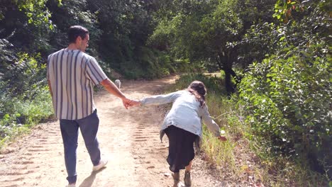 Ein-Mann-Und-Eine-Frau-Gehen-Hand-In-Hand-Mit-Ihrem-Hund-In-Einem-Wald-In-Zeitlupe,-Pflücken-Löwenzahn-Und-Blasen