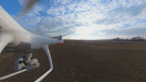 close-up side view of dji phantom 4 quadcopter drone flying forward over fields