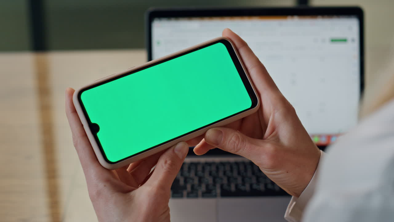 las manos del director mirando el teléfono móvil de pantalla verde. los dedos de la dama sosteniendo el teléfono