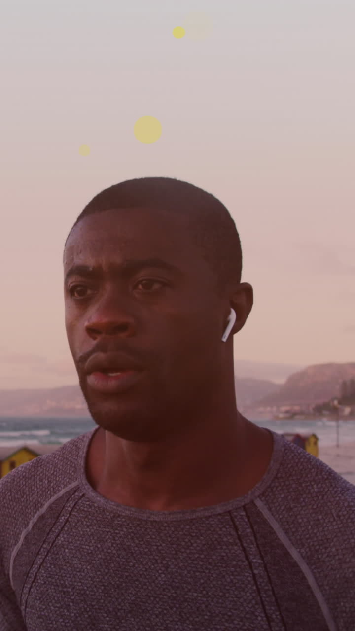 manchas amarillas flotando contra afroamericano hombre en forma corriendo en el paseo marítimo