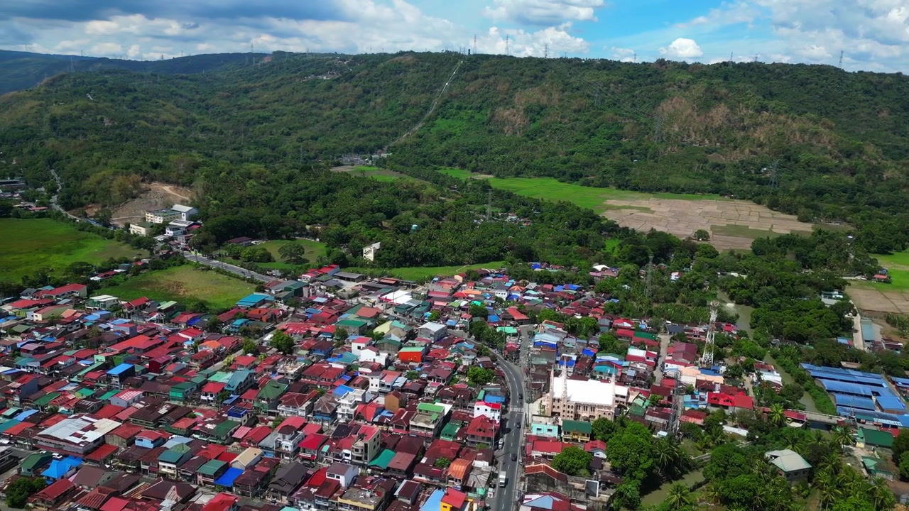 Perspektif udara drone Kotamadya Lumban di Laguna, Filipina yang menangkap kehidupan kota provinsi, vegetasi tropis, dan pemandangan pegunungan terdekat