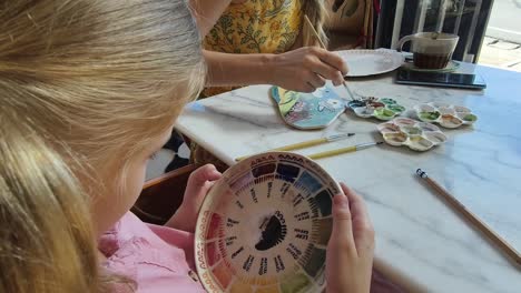 girl and adult painting ceramic art at a cafe