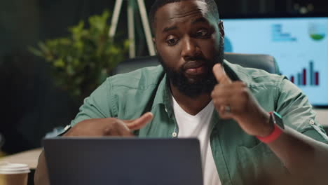 Focused-afro-business-man-discussing-project-by-video-chat-in-night-office