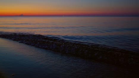 closeup sea waves splashing dark sand beach. golden skyline horizon view