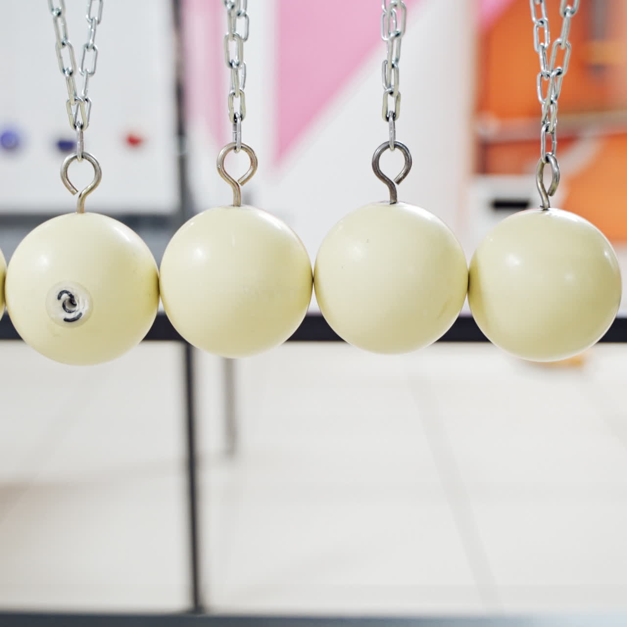 Hand holding a pendulum ball. Newton's cradle