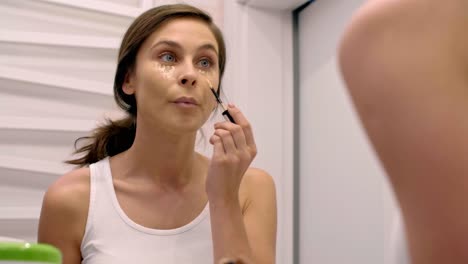 woman applying concealer on her face in bathroom